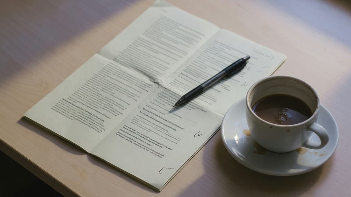 Illustrative planning scene with a written brief, a pen and a cup of coffee